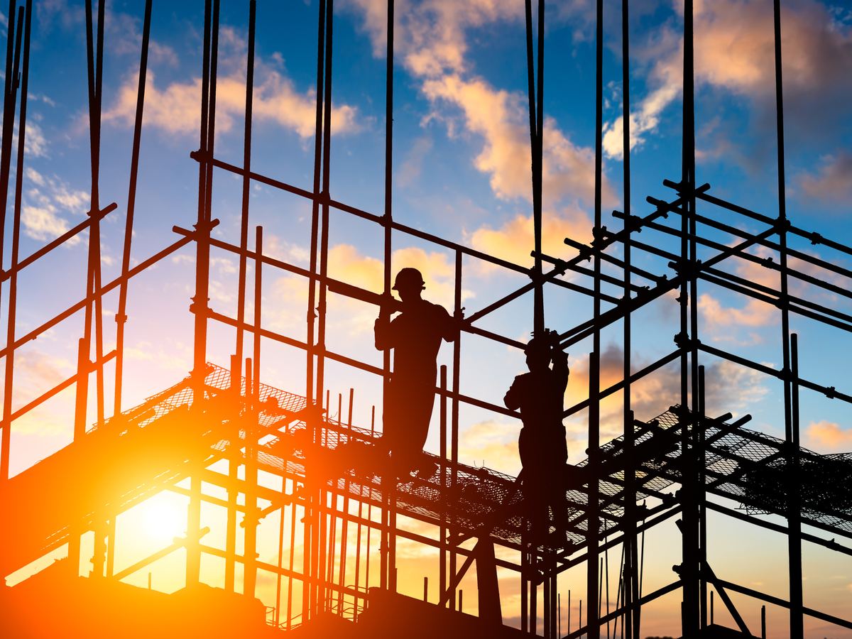Site workers on scaffolding at sunset